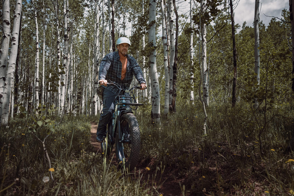 A man riding the Alpine Fat Tire Electric Bike on an off road forest trail.