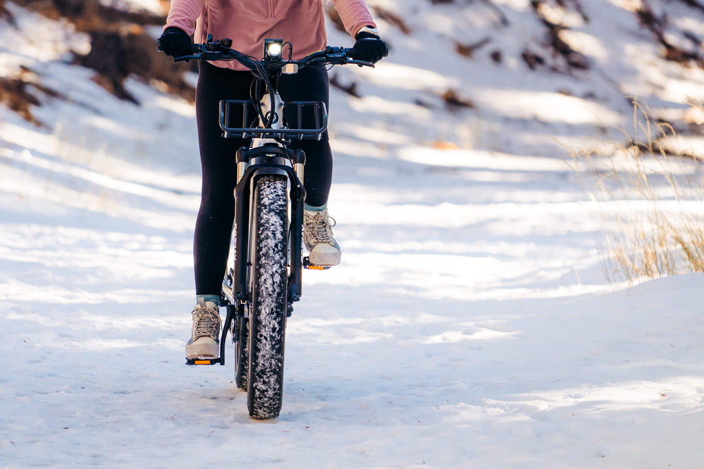 A woman riding the GOTRAX Tundra Fat Tire Electric Bike in the snow.